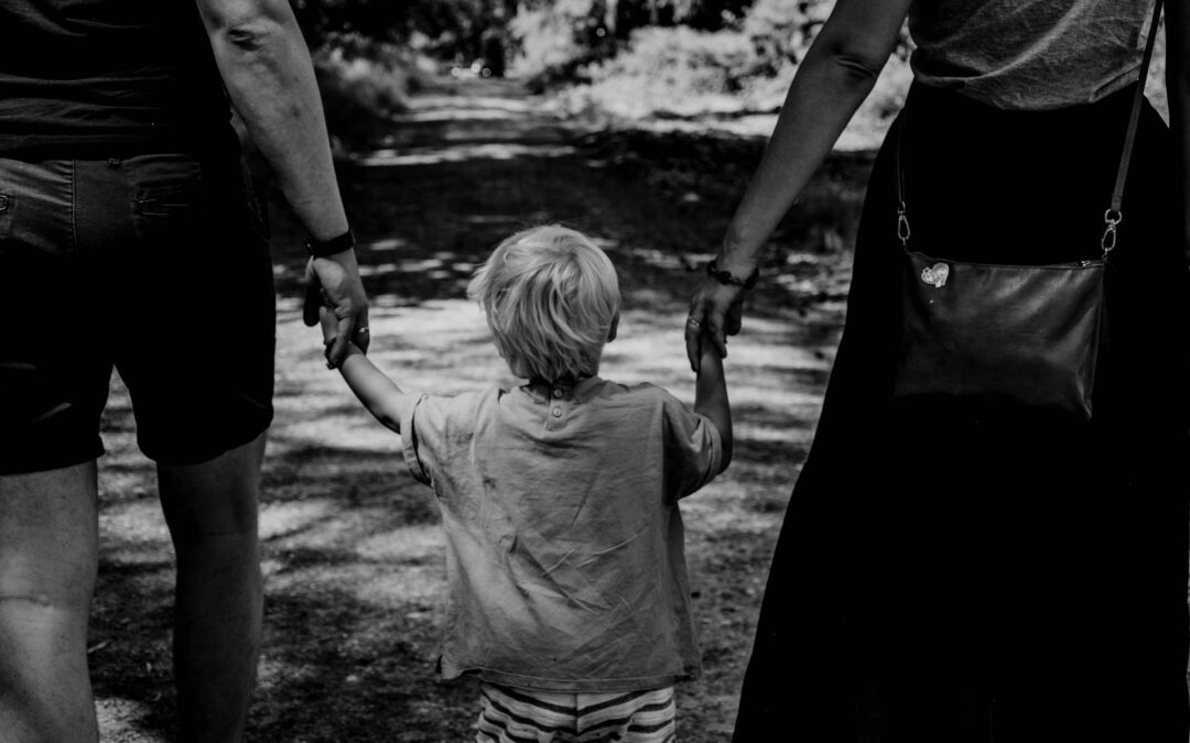 Couple holding hands with child.